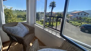 A room with wicker furniture, large windows, and a view of a residential area. - Vivienda Vacacional La Mata Vieja (La Franca)
