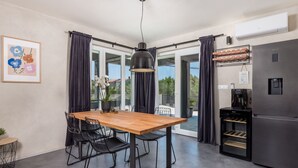 A modern kitchen with a wooden table and black chairs, a stainless steel refrigerator, and a coffee machine. - Villa Nika by Interhome (Krk/Dobrinj)