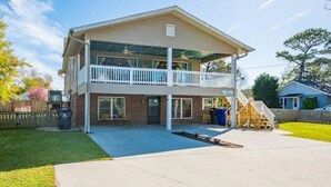 A two-story house with a covered balcony, a front porch, and a visible staircase leading to the second floor. - Beach Daze Duplex - Unit B! Fenced-in backyard! Pets Welcome! 5 Blocks to beach! (Carolina Beach)