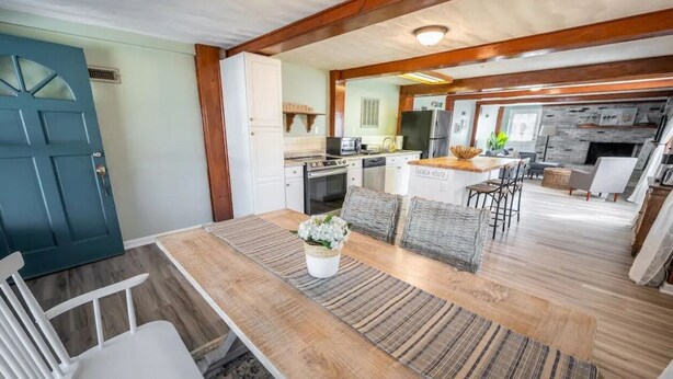 A spacious kitchen with modern appliances, a dining area with a wooden table and chairs, and a cozy living area with a fireplace. - Beach Daze Duplex - Unit B! Fenced-in backyard! Pets Welcome! 5 Blocks to beach! (Carolina Beach)