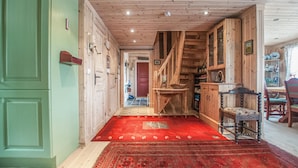 Een houten interieur met een rood tapijt, houten kasten en een trap.