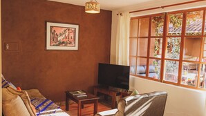 Een woonkamer met een bank, een televisie en een raam met uitzicht op het landschap.