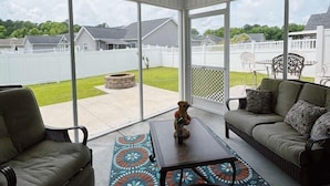 A covered patio area with a ceiling fan, a sofa, a chair, and a coffee table. - Coastal Oasis: Games, Pool, BBQ & beach (Myrtle Beach)