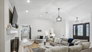 A spacious living room with a large sofa, a fireplace, and a dining area.