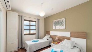 A hotel room with two beds, a window with curtains, a painting on the wall, and a ceiling light. - Vista Lobos (La Oliva)