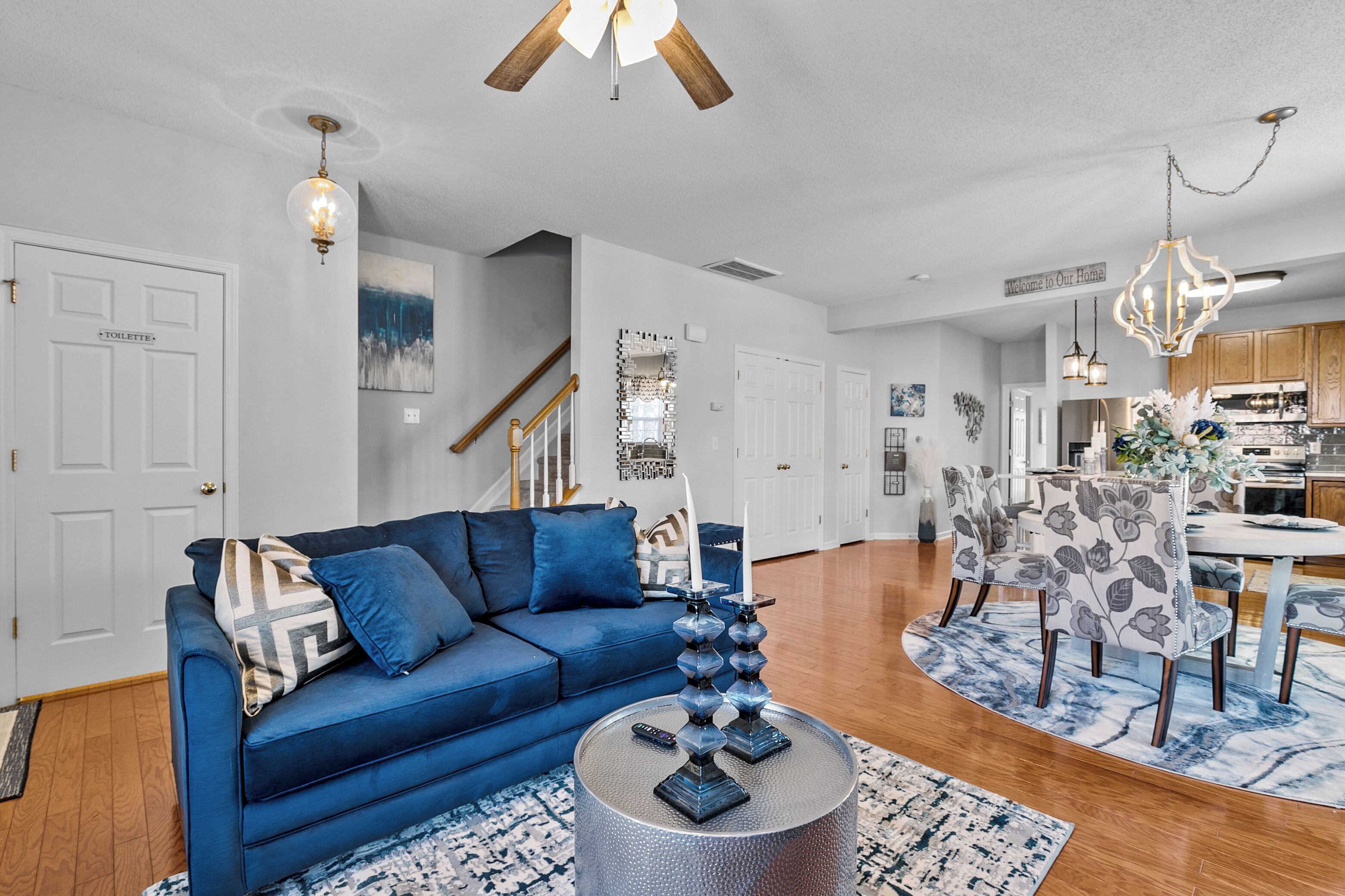 Un salon moderne avec un canapé bleu, une table basse et un coin repas agrémenté de chaises à motifs floraux.