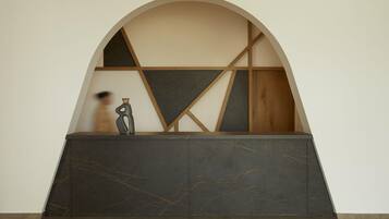 A reception desk with a modern design, featuring a dark marble top and a geometric wooden structure in the background.