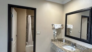 A bathroom with a sink, mirror, and shower. - HYLAND MOTEL (La Habra)