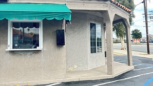 A building with a tiled roof, a green awning, and a window with a metal sign. - HYLAND MOTEL (La Habra)