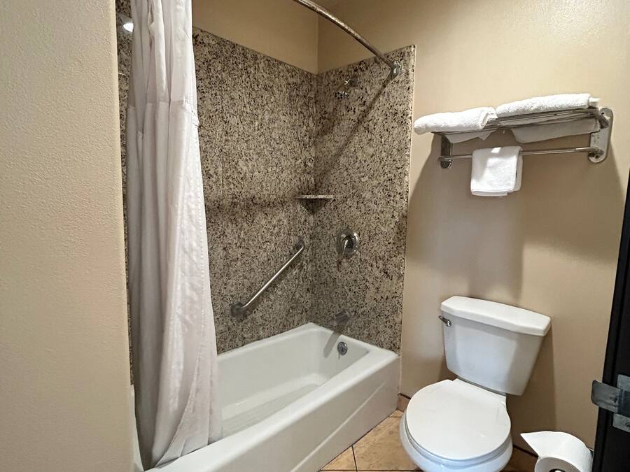Un bagno con vasca, water e tenda da doccia.