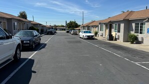 A parking lot with cars parked in rows, a clear sky, and buildings with a uniform architectural style. - HYLAND MOTEL (La Habra)