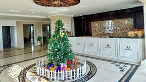 A lobby with a Christmas tree, a reception desk, and a patterned floor. - Union Inn (Tuan Chau)