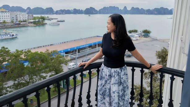 A balcony with a railing overlooking a body of water with boats, a dock, and buildings in the background. - Union Inn (Tuan Chau)