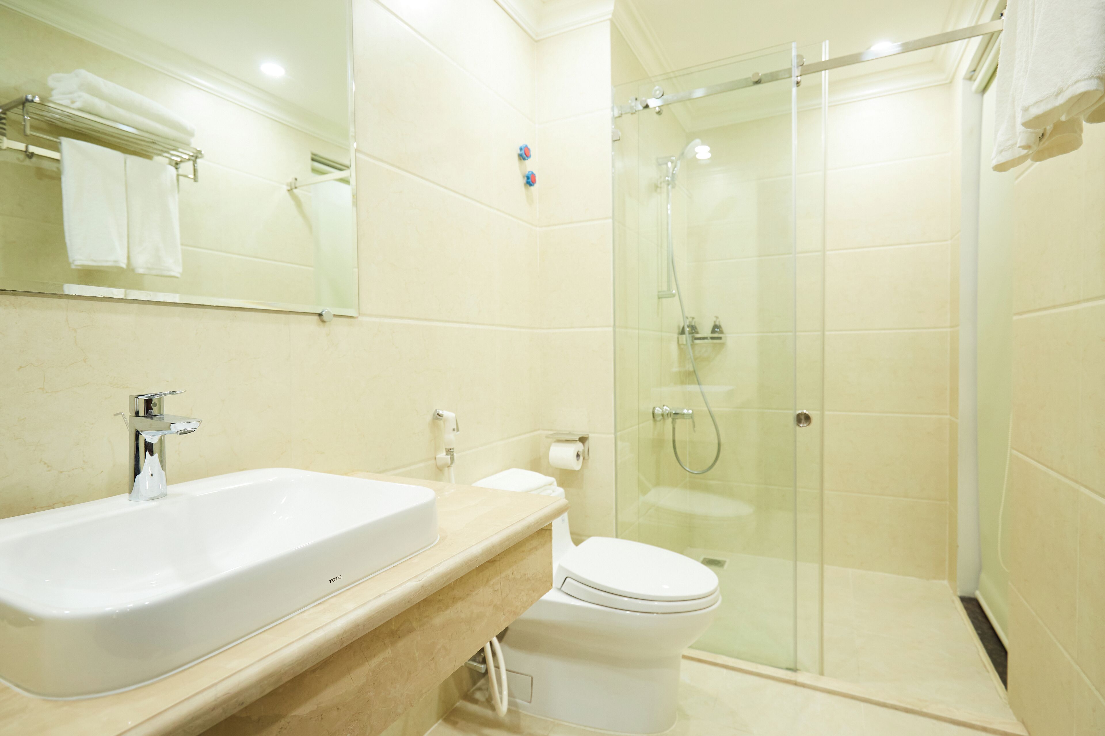 A modern bathroom with a large sink, toilet, and glass-enclosed shower.