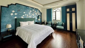A spacious bedroom with a large bed, a nightstand, a chair, and a wardrobe. - Union Inn (Tuan Chau)