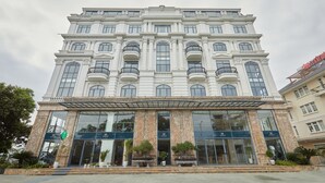 A large, multi-story hotel with a classical architectural style, featuring a grand entrance with a covered walkway and potted plants. - Union Inn (Tuan Chau)