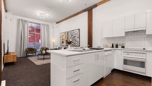 A modern kitchen with white cabinetry, a central island, and a built-in oven. - 1 BR Apartment In the Heart of Darling Harbour (Pyrmont)
