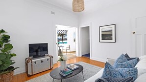 Una sala de estar moderna con un sofá, una mesa de centro, un televisor en un mueble y vistas al exterior.