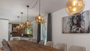 A modern dining area with a long wooden table, multiple chairs, and pendant lighting. - Visum Mare Tribus by Interhome (Mošćenička Draga)