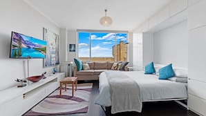 A modern bedroom with a large window, a bed, a sofa, and a TV on the wall. - Centennial Park Light Filled Modern Studio (Centennial Park)