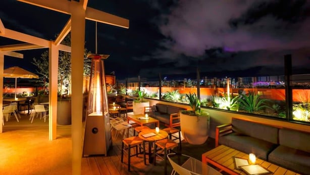 An outdoor seating area with tables and chairs, a hanging light fixture, and potted plants. - Centennial Park Light Filled Modern Studio (Centennial Park)