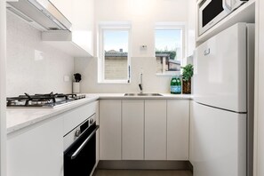 Une cuisine de taille réduite équipée d’une cuisinière à gaz, d’un four, d’un four à micro-ondes et d’un réfrigérateur.