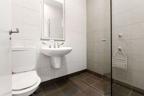 Une salle de bain comprenant des toilettes, un lavabo et une douche à parois en verre.