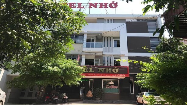 Un bâtiment avec une enseigne indiquant « EL NHÔ » et une devanture de magasin avec une enseigne qui dit « Cafê ».