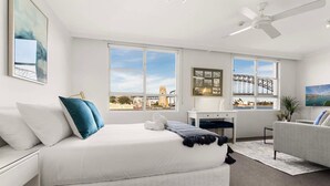 Une chambre d’hôtel moderne dotée d’un grand lit, d’un bureau, d’un canapé et de grandes fenêtres offrant une vue sur la ville.