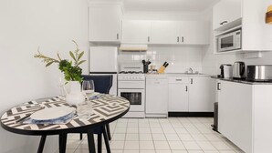 Une cuisine moderne avec des meubles blancs, une cuisinière à gaz, un four à micro-ondes et une machine à café.