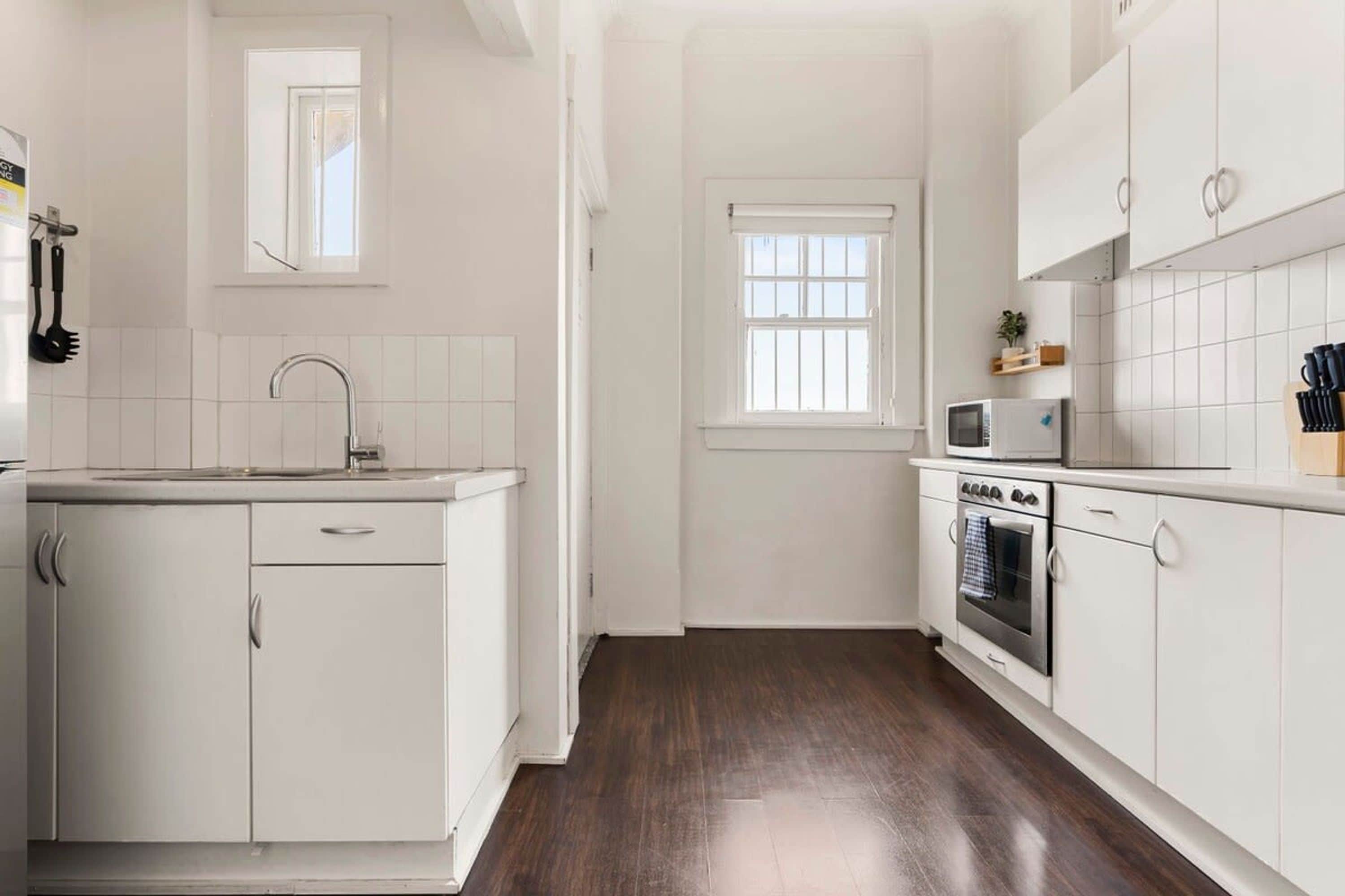 A kitchen with white cabinets, a microwave, and a stove.