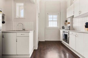 A kitchen with white cabinets, a microwave, and a stove. - Lovely Apartment in Darlinghurst (Darlinghurst)