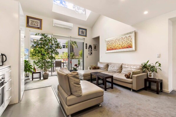 A modern living room with a sofa, coffee table, and a dining area with a table and chairs.