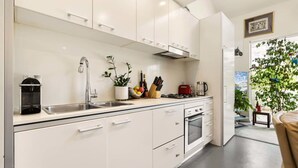 A modern kitchen with white cabinets, a stainless steel sink, a coffee machine, and a gas stove. - Poolside Apartment Opposite Redfern Park (Redfern)
