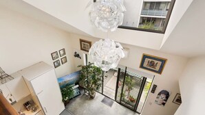 A modern interior with a high ceiling, a dining area with a view, and a balcony with a railing. - Poolside Apartment Opposite Redfern Park (Redfern)
