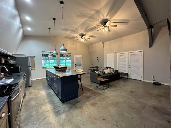 A spacious kitchen with a central island, a dining area with a sofa, and a ceiling fan. - The Cottage at She Boss Farmstead (Lexington)