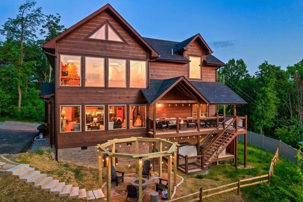 Een houten chalet met twee verdiepingen, meerdere ramen, een overdekt terras en een trap naar een hoger niveau.