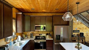 A modern kitchen with wooden cabinets, stainless steel appliances, a built-in microwave, and a coffee bar.