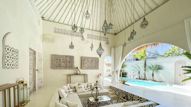 A spacious living area with a curved sofa, a coffee table, and a view of a swimming pool. - Casa Blanca (Canggu)