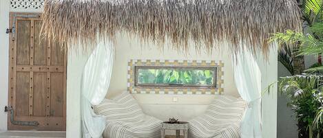 A pool area with a thatched roof structure, a wooden door, and a framed picture on the wall.