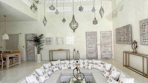 A spacious living room with a large L-shaped sectional sofa, a coffee table, and hanging geometric pendant lights. - Casa Blanca (Canggu)