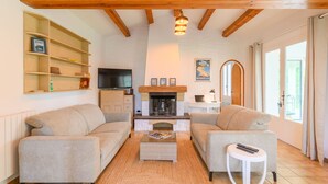 Ein gemütliches Wohnzimmer mit zwei Sofas, einem Kamin, einem Fernseher und einem Bücherregal.