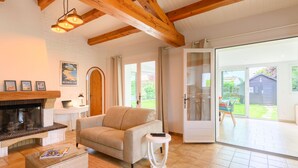 Ein Wohnzimmer mit Kamin, einer Couch, einem Couchtisch und Blick ins Freie.