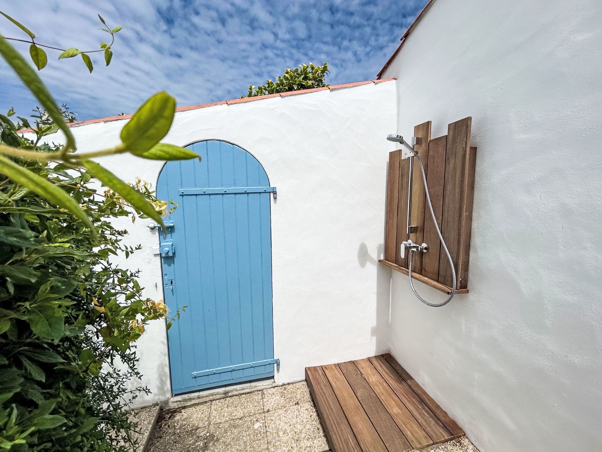 Une porte bleue, un banc en bois et un espace douche avec des panneaux en bois.