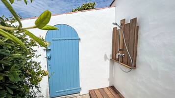 Una porta blu, una panca di legno e un angolo doccia con pannelli di legno.