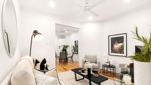A modern living room with a sofa, coffee table, and a glass table with a plant. - Comfy Darlinghurst Retreat (Darlinghurst)