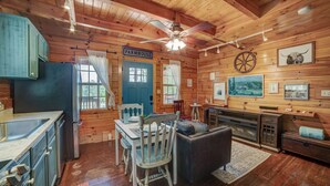 L’intérieur d’un chalet rustique comprenant un coin repas, une cuisine et un espace de vie.