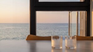 Taula amb dos vasos i vista al mar a través d'una finestra.