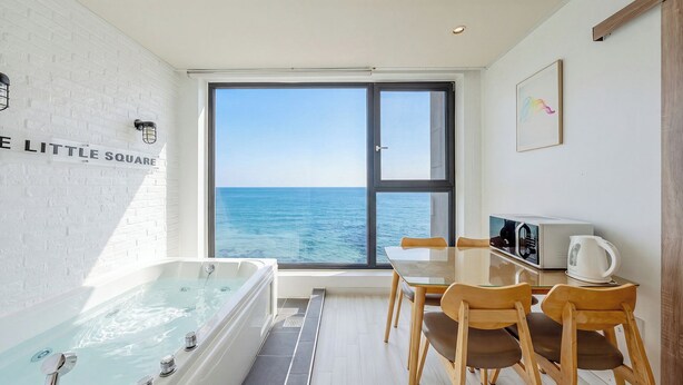 Habitació amb banyera, taula amb cadires, una papereta tè i vista al mar.