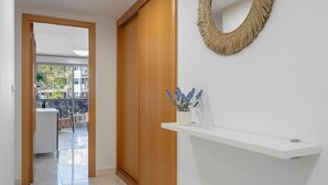 A hallway with a wooden door, a white reception desk, and a woven mirror on the wall. - Apartment with pool and parking 350m beach (Cambrils)